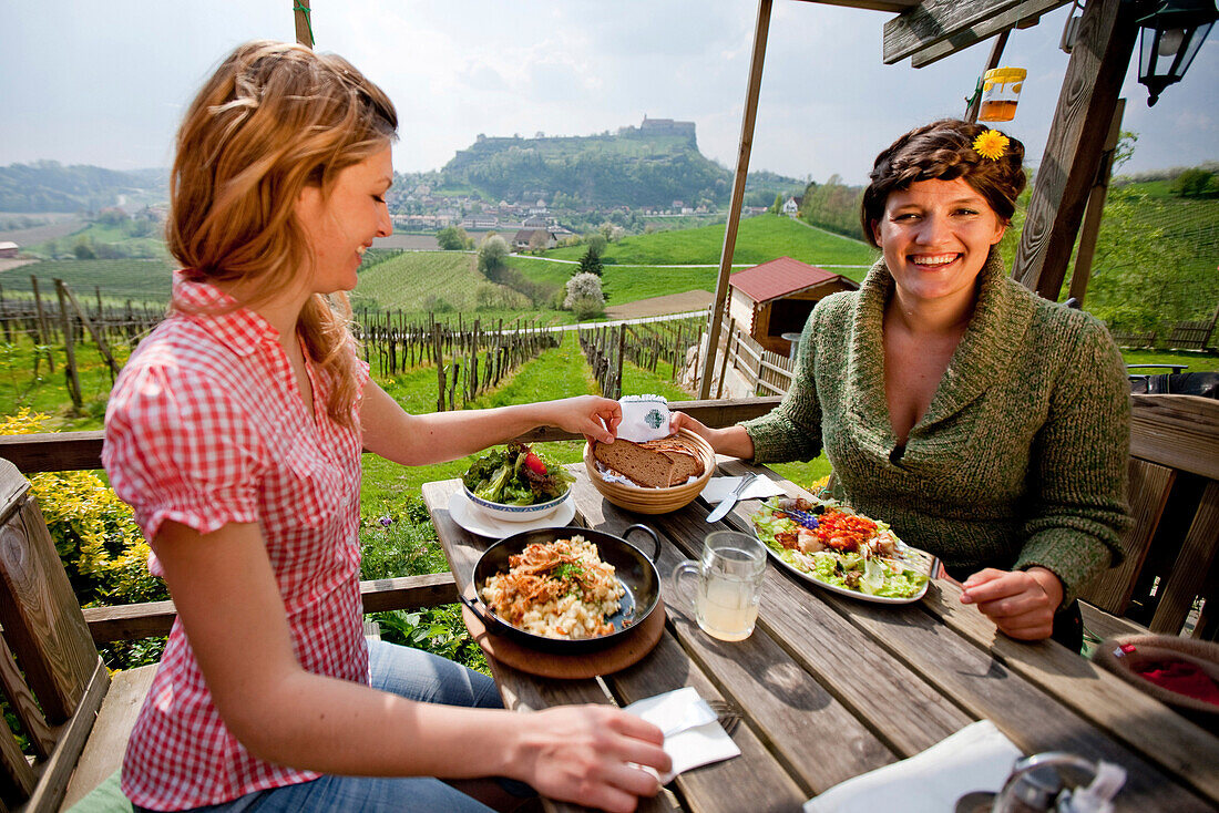 Two young women having lunch, Riegersburg castle in background, Riegersburg, Styria, Austria