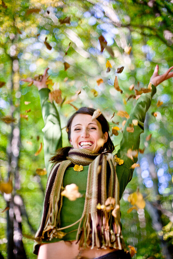 Junge Frau wirft Herbstlaub hoch, Steiermark, Österreich