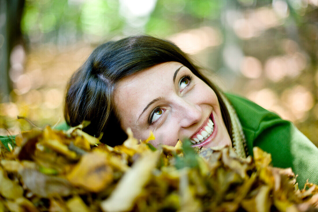 Junge Frau liegt im Herbstlaub, Steiermark, Österreich