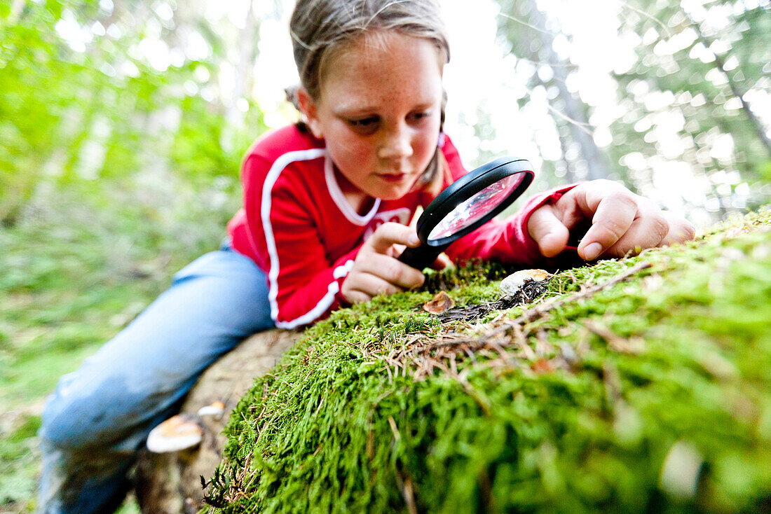 Girl looking at plant through magnifying glass, Styria, Austria