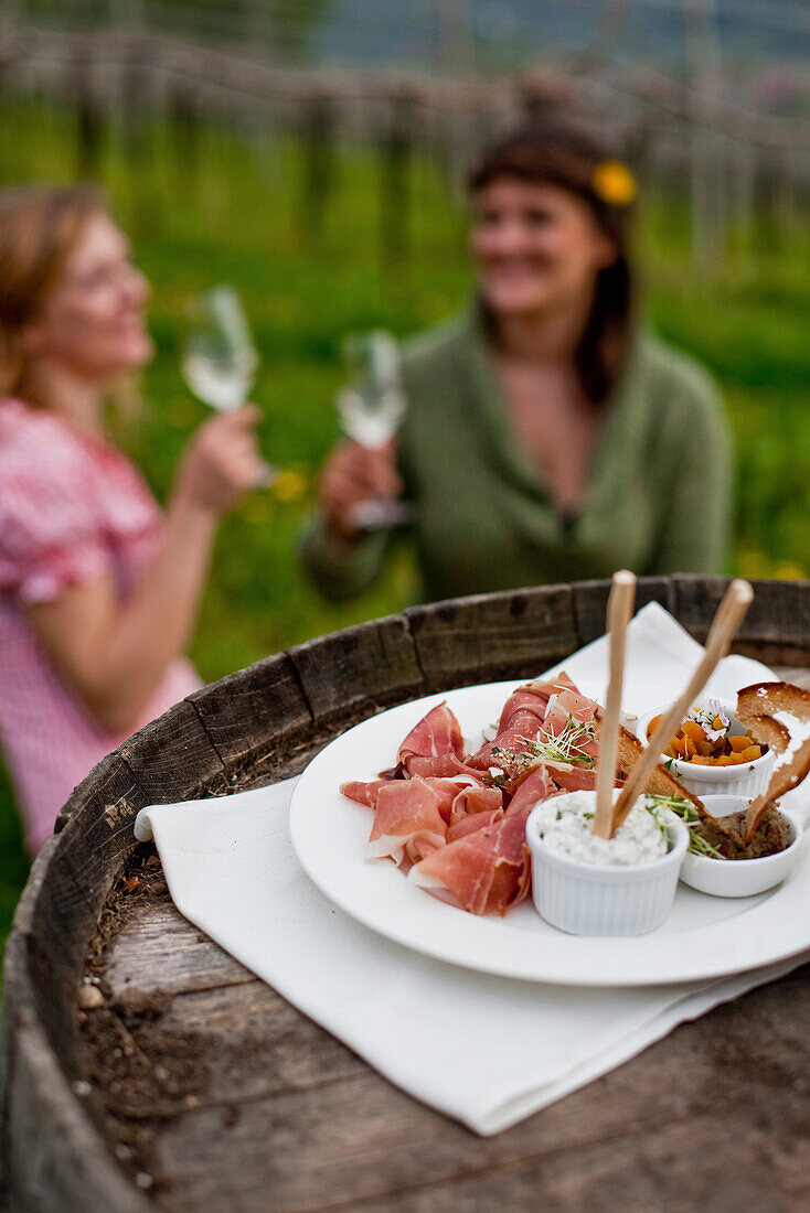 Zwei junge Frauen genießen lokale Spezialitäten in einem Weinberg, Riegersburg, Steiermark, Österreich