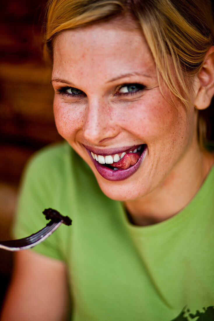 Young woman eating pancake with blueberries, lake Duisitzkar, Styria, Austria