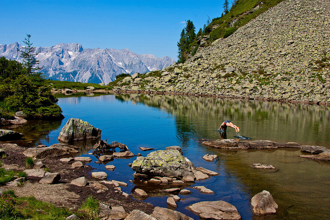 Man jumping into lake Spiegelsee, Dachstein mountains in background, Styria, Austria