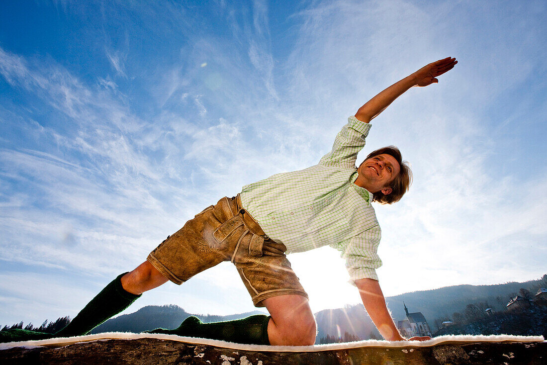 Young man doing yoga wearing traditional Austrian outfit, Styria, Austria