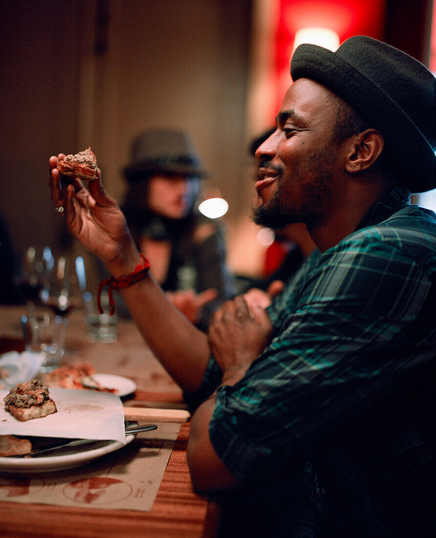 USA, California, Los Angeles, man holding and eating pizza at Pizzeria Mozza.