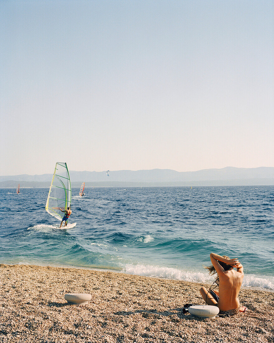 CROATIA, Bol, Brac, Dalmatian Coast, sunbather and windsurfer in Zlatni Rat Beach.