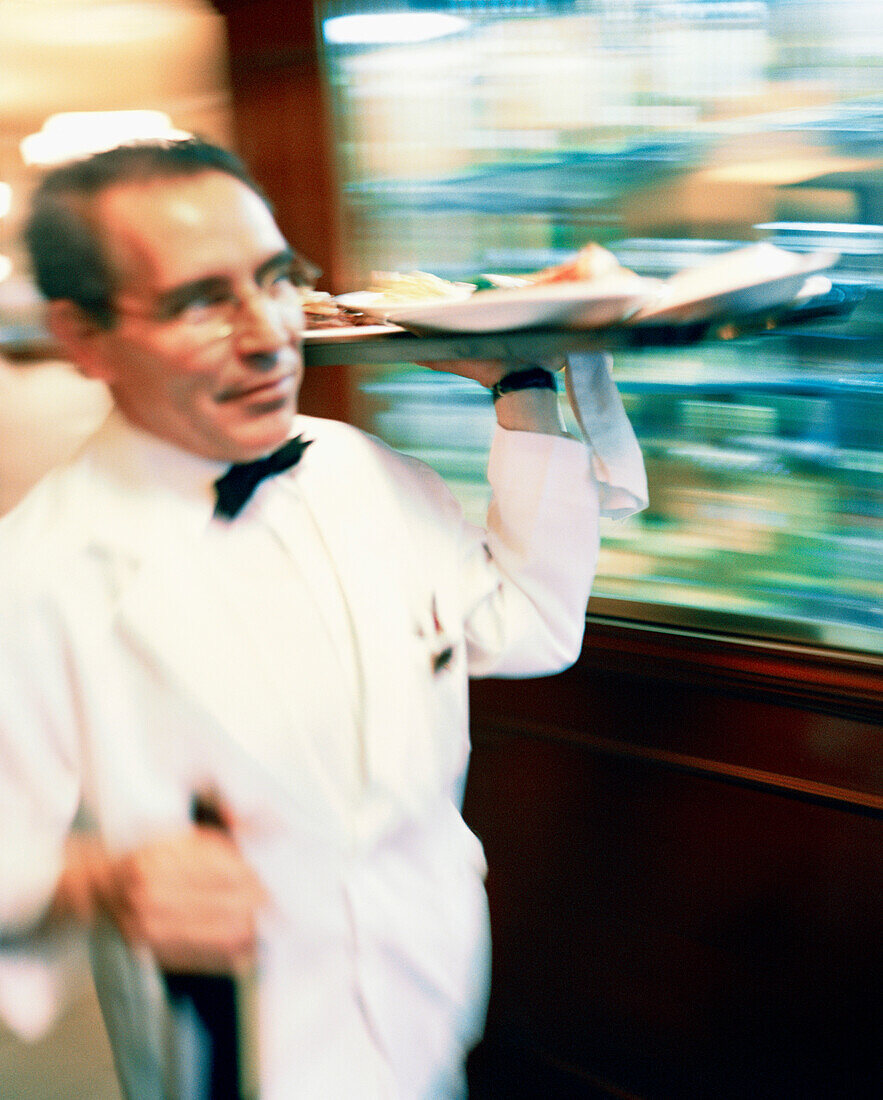 MEXICO, Mexico City, waiter carrying tray of food and bottle at Danubio Restaurant.