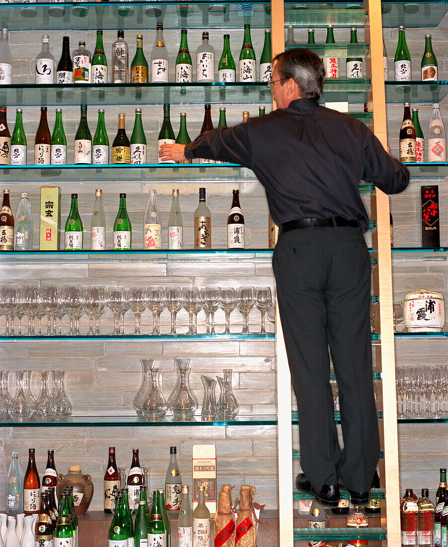 USA, Nevada, Las Vegas, bartender arranging bottle of wine at Okada Restaurant.
