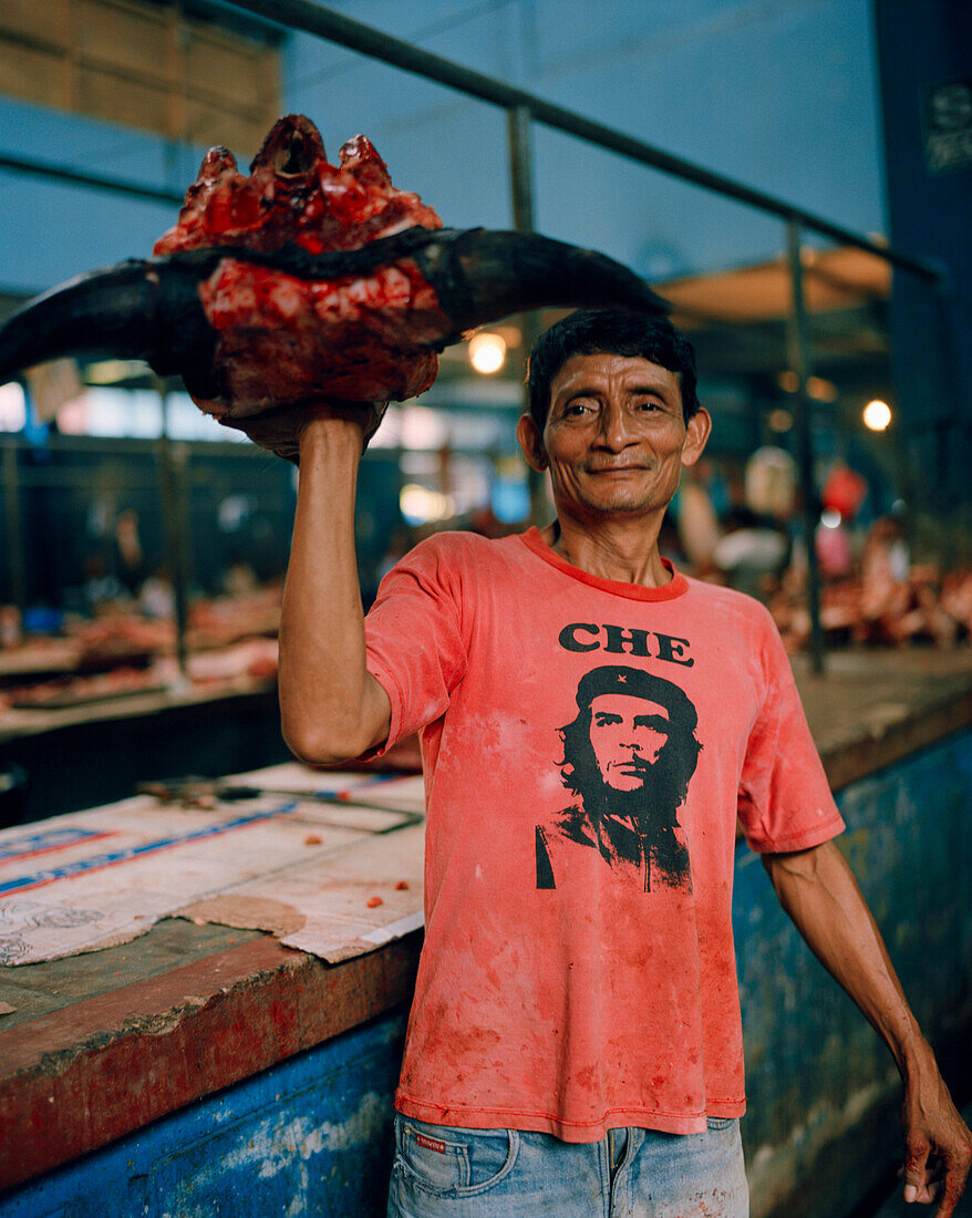 PERU, Amazon Rainforest, Belen, South America, Latin America, portrait of a mature man holding animals head at the Belen Market.