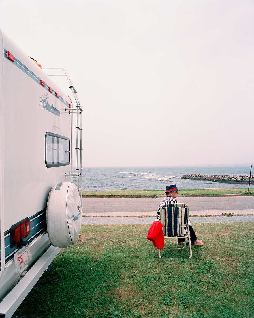 USA, Rhode island, Newport, relaxed mid adult man sitting in beach chair next to his motorhome.