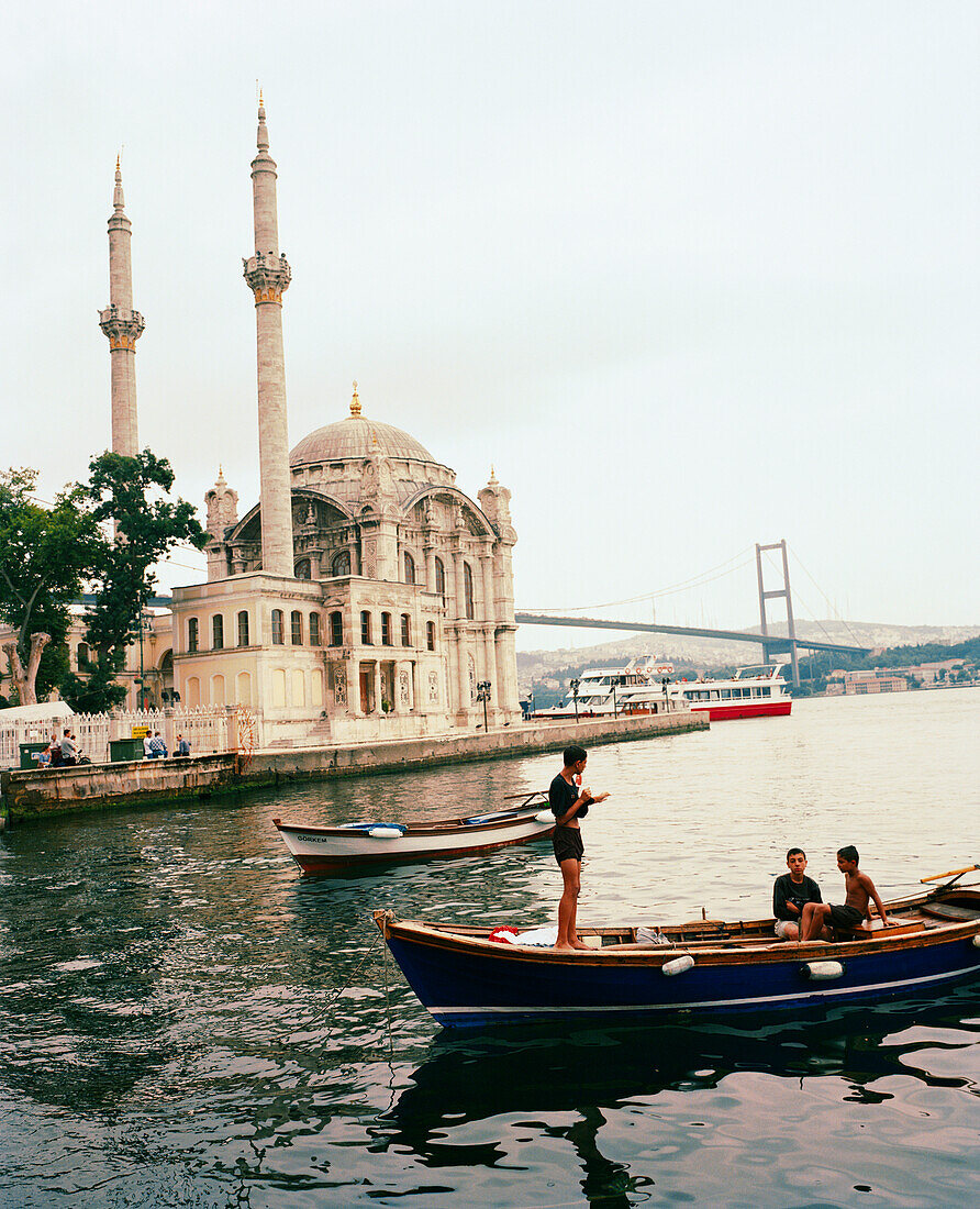 TURKEY, Istanbul, teenage boys on boat with Ortakoy Mosque in the background