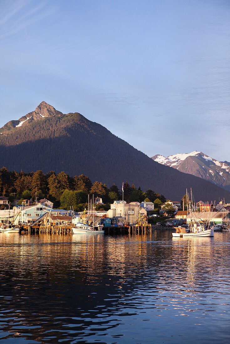 ALASKA, Sitka, a peaceful view of homes and fishing boats along the shore in Sitka Harbor at sunset, Mount Verstovia peak in the distance