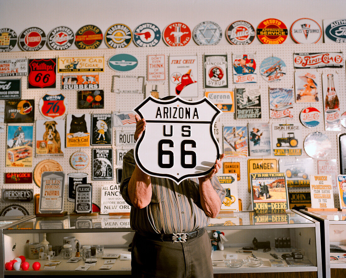USA, Arizona, man holding sign Arizona US 66 in a sign store, Holbrook