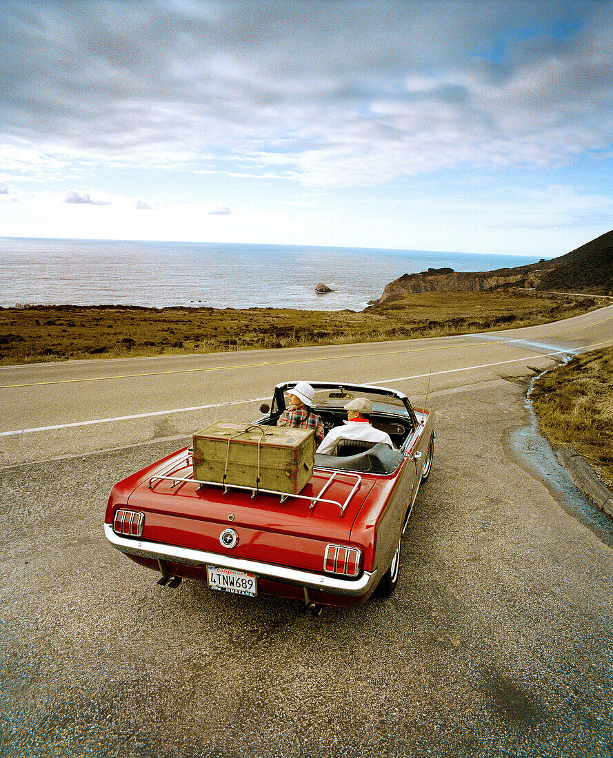 USA, California, Big Sur, couple on a road trip in a 1965 Ford Mustang, Hwy 1