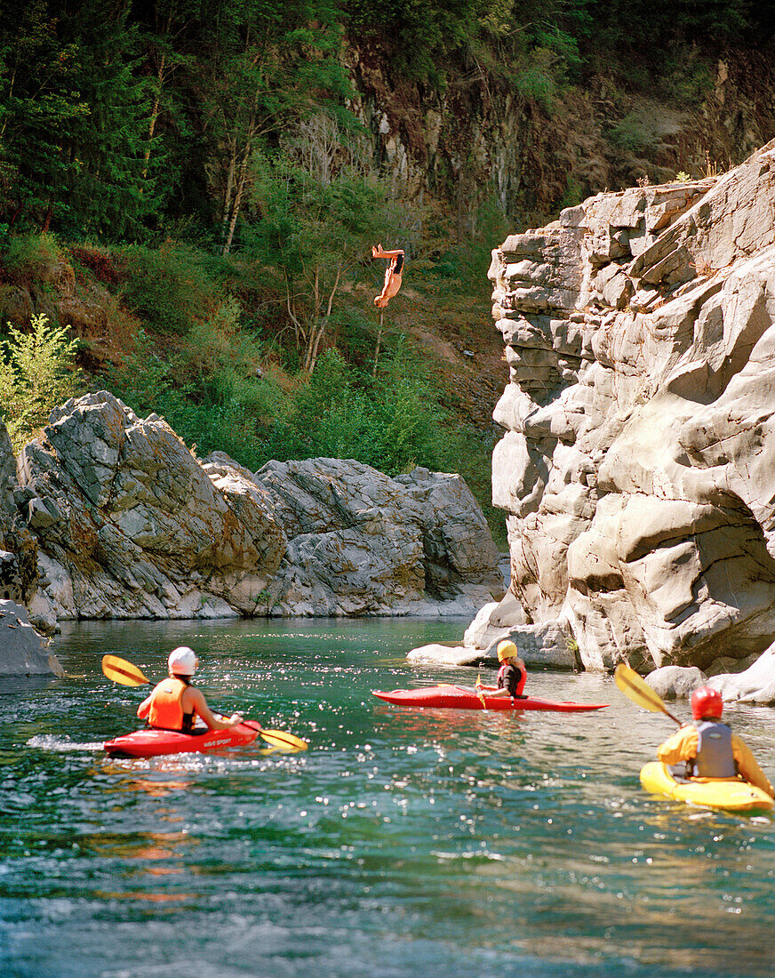 USA, California, people kayaking Salmon River and man diving off rocks, Forks of Salmon