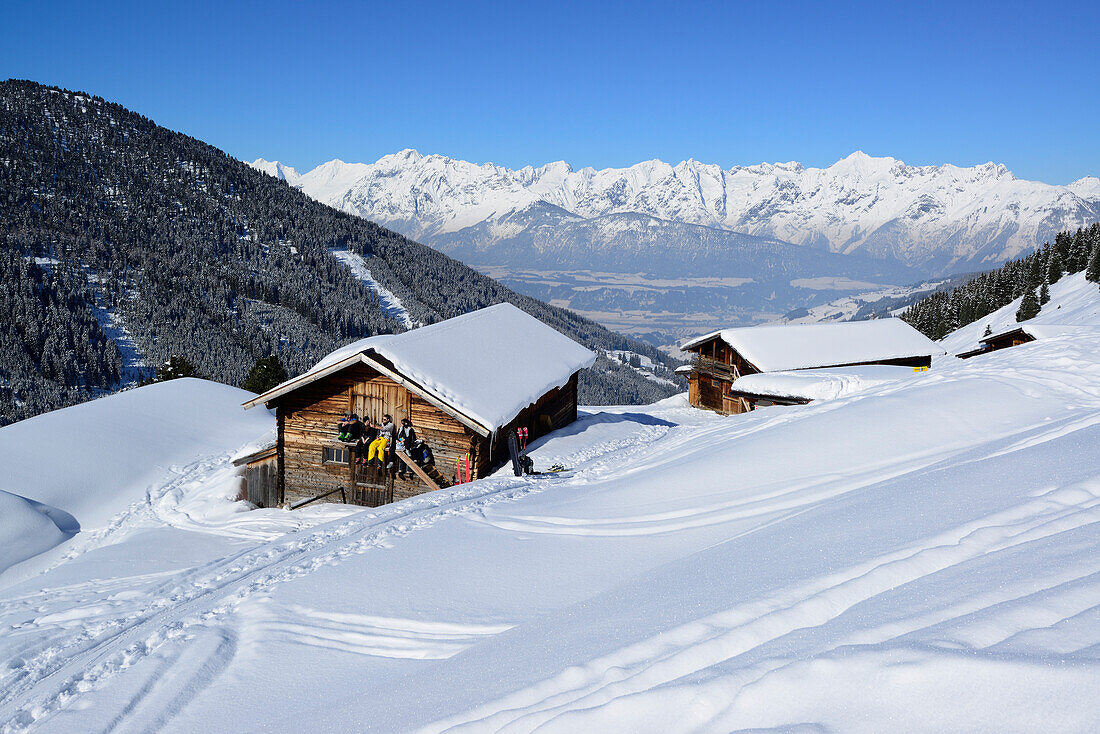 Gruppe von Skitourengehern macht an verschneiter Almhütte Pause, Skitour, Hoher Kopf, Tuxer Alpen, Tirol, Österreich