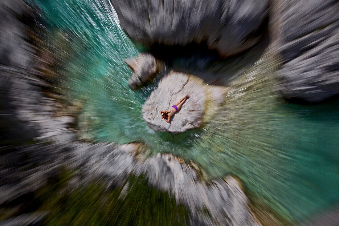 Junge Frau sonnt sich auf einem Felsen im Fluss Soca, Alpe-Adria-Trail, Tolmin, Slowenien