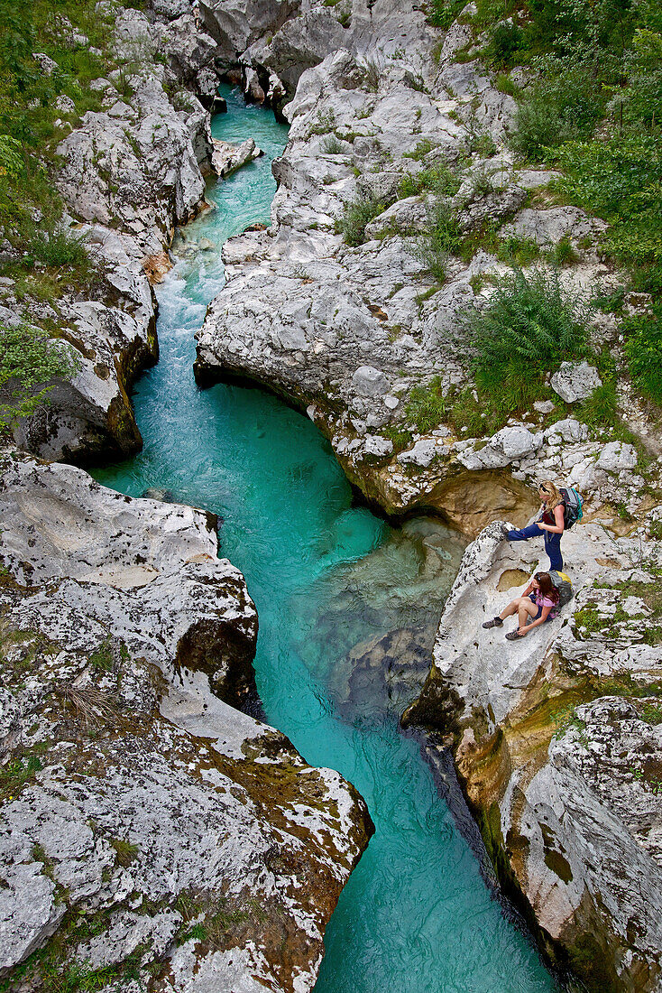 Zwei Wanderinnen blicken von einem Felsen auf den Fluss Soca, Alpe-Adria-Trail, Tolmin, Slowenien