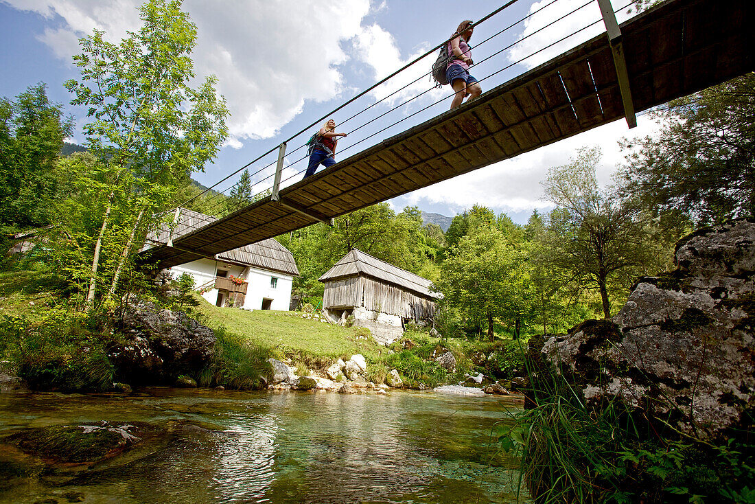 Two female hikers passing a swing bridge, Alpe-Adria-Trail, Trenta,  Slovenia