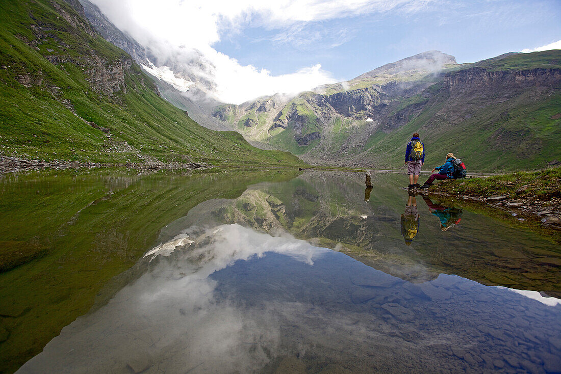 Two female hikers resting at a riverbank, Nockberge, Carinthia, Austria