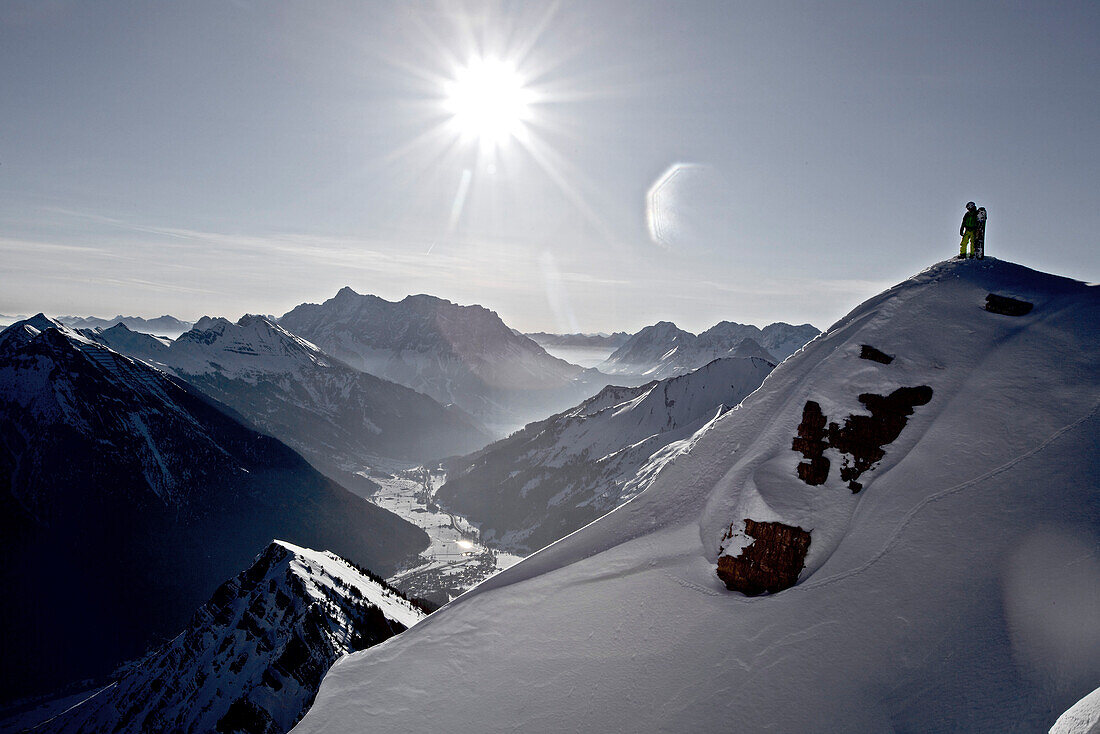 Snowboarder steht auf einem Berggipfel, Thaneller, Lechtaler Alpen, Tirol, Österreich