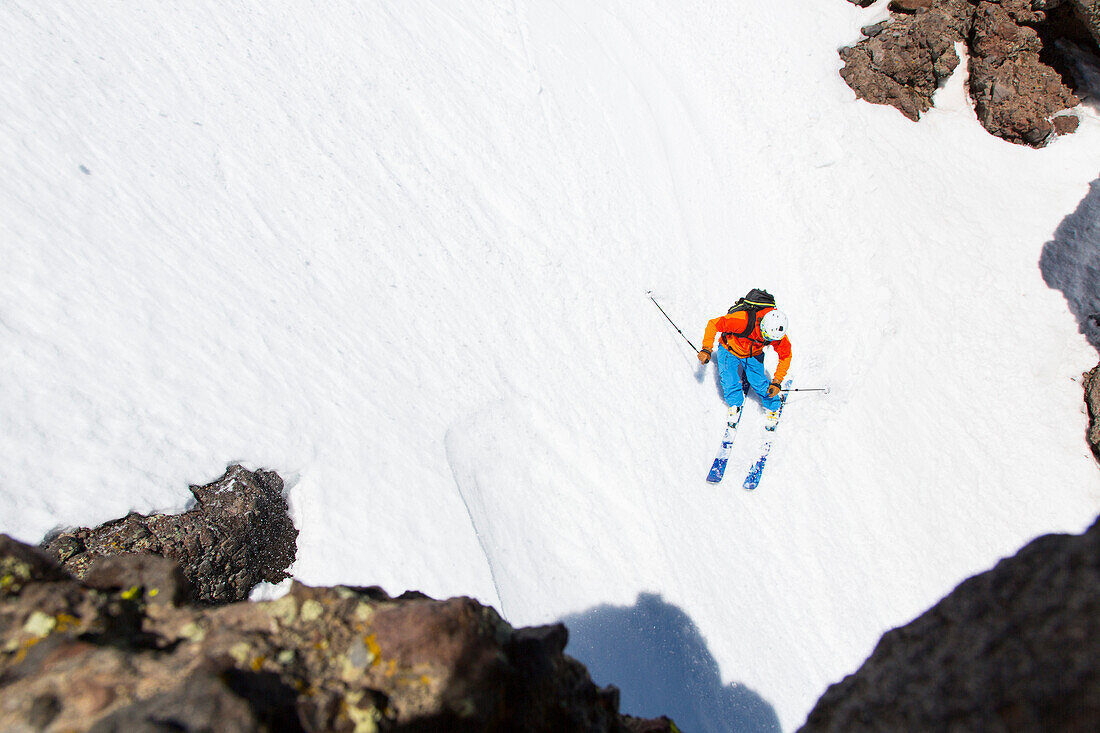 Skifahrer fährt durch eine Rinne mit Lava-Gestein, Skigebiet Kirkwood, Kalifornien, USA