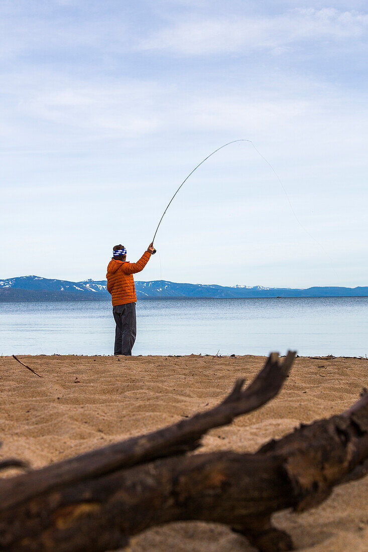 Fly fisherman at the beach of Lake Tahoe, California, USA