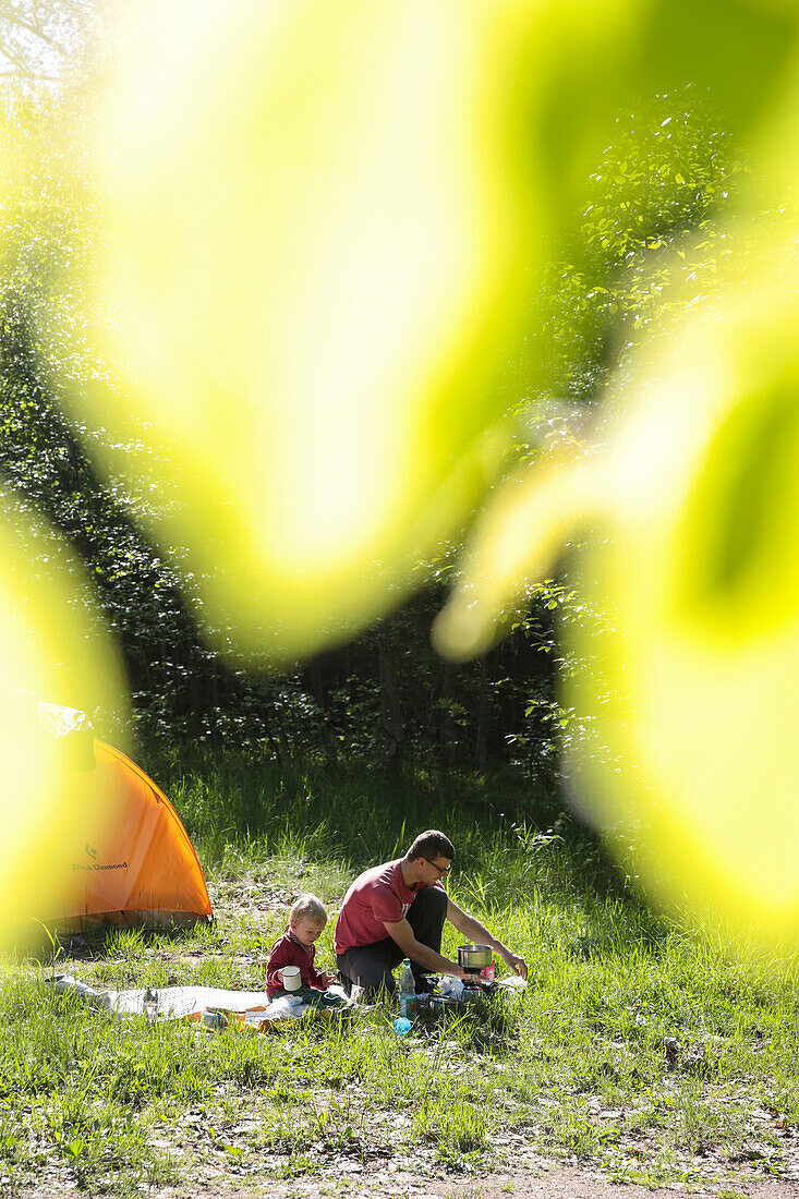 Father and son having breakfast in front of a tent, near Boitzenburg, Uckermark, Brandenburg, Germany