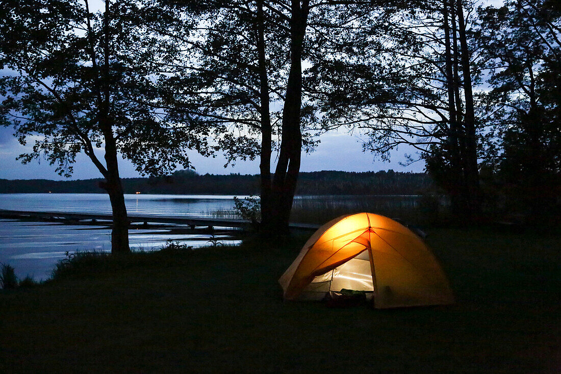 Illuminated tent at lakeside, Lychen, Uckermark Lakes Nature Park, Uckermark, Brandenburg, Germany