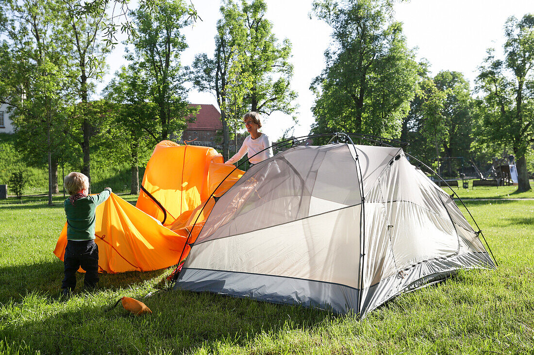 Mother and son (2 years) putting up a tent, Wesenberg, Mecklenburg-Western Pomerania, Germany