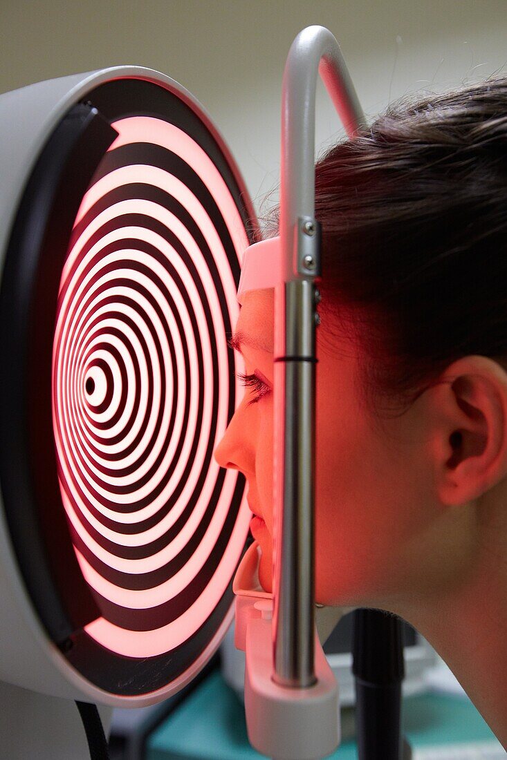 Eye examination  Patient having a corneal topography measurement made of her eye  The device at centre projects bright rings onto the eye, which are reflected in its surface  By studying the reflection, an accurate model can be built up of the shape of he