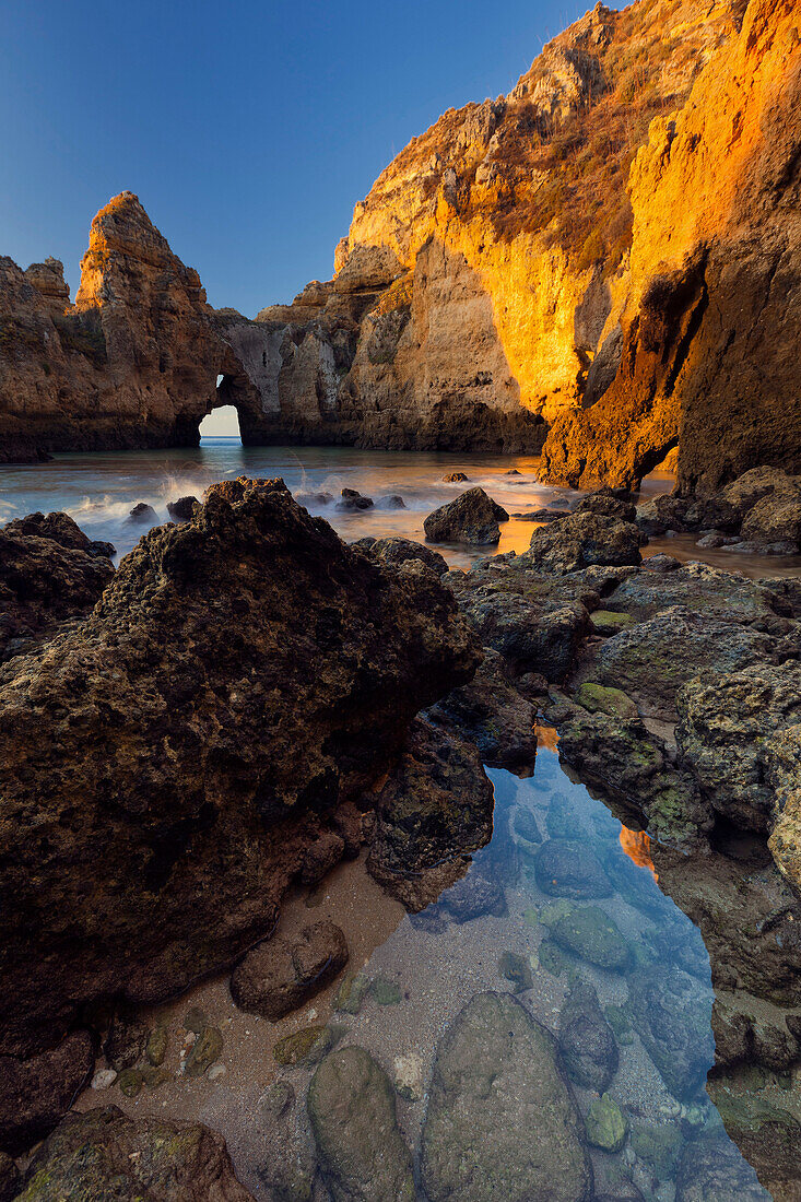 Gelbe Felsen der Algarve in der Morgensonne mit glasklarem Atlantikwasser und strahlend blauem Himmel, Algarve, Portugal