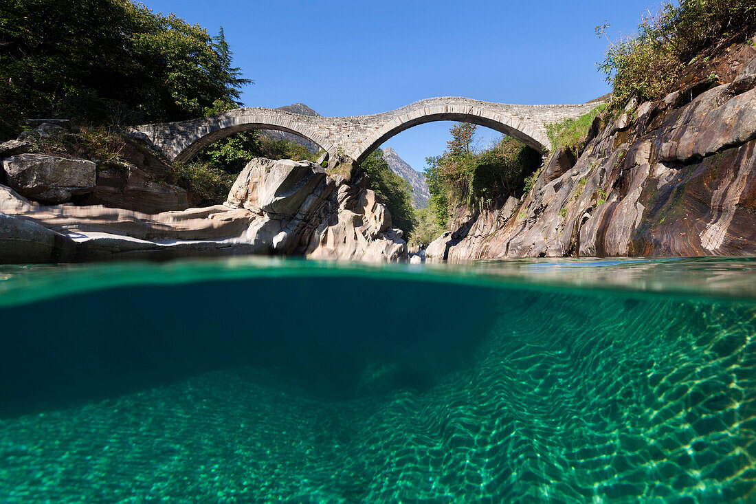 View beneath the water surface of the mountain river Verzasca near Lavertezzo with the historic bridge Ponte dei Salti in the Swiss Alps, Canton of Ticino, Switzerland