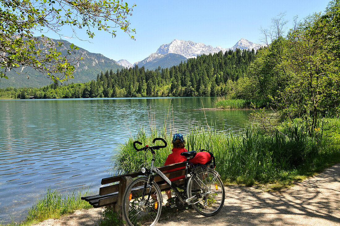 Cyclist taking a rest at Lake Barmsee, Karwendel mountain range near Kruen, Bavaria, Germany