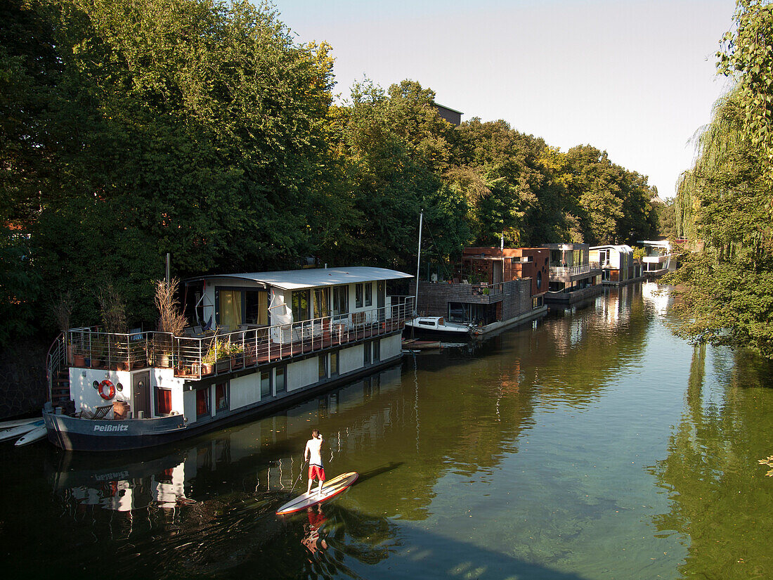 Stand Up Paddling auf einem Kanal mit Hausbooten, Hansestadt Hamburg, Deutschland