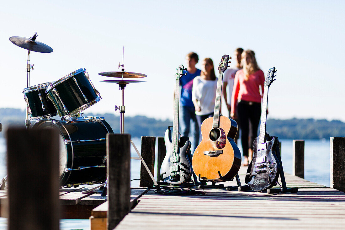 Musikinstrumente auf einem Steg am Starnberger See, vier Personen im Hintergrund, Bayern, Deutschland