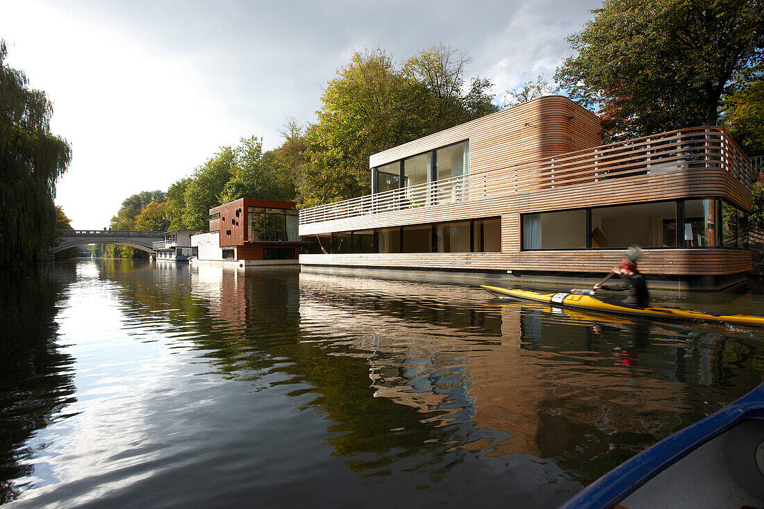 Canoe on Eilbek canal passing a houseboat, Hamburg, Germany