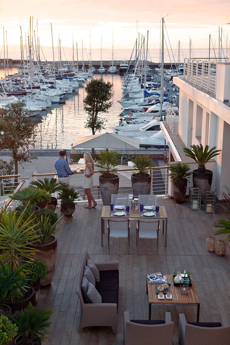 Couple on the terrace of a restaurant looking at the marina at dusk