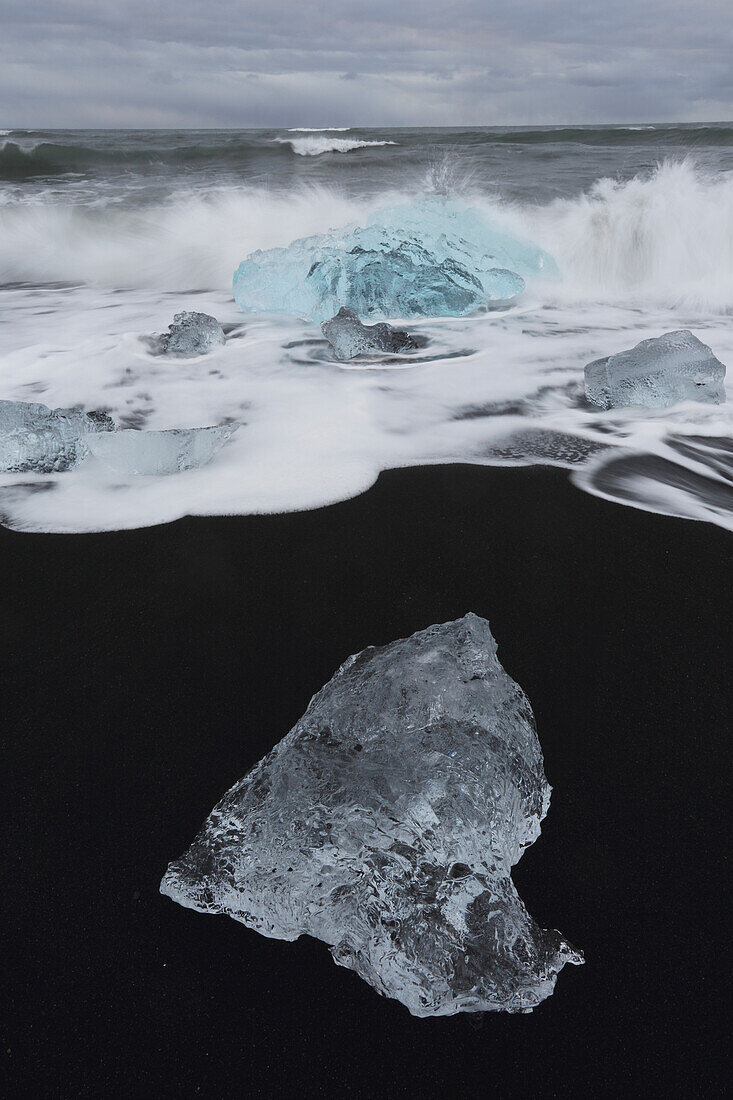 Waves from the atlantic ocean crash into ice calf from breioamerkurjokull a glacial tongue of the vatnajokull ice cap, iceland