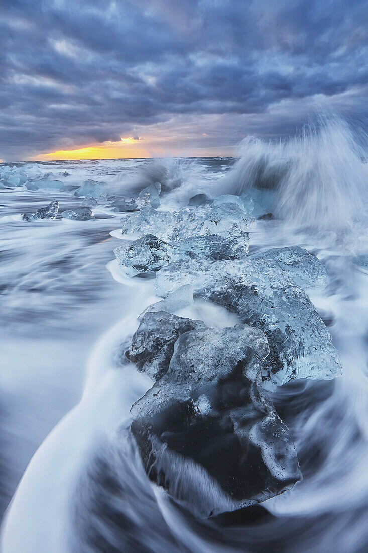 Waves from the atlantic ocean crash into ice calf from breioamerkurjokull a glacial tongue of the vatnajokull ice cap, iceland