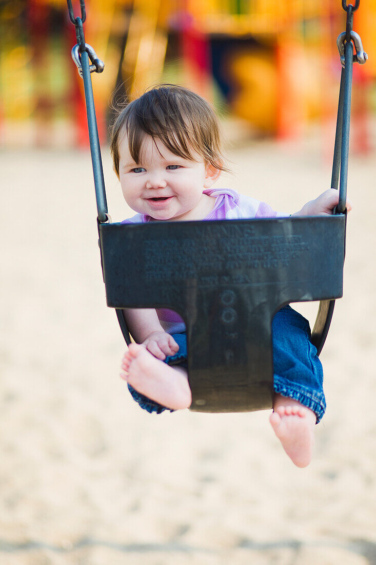 Happy 6-month-old baby girl in a swing by a park, ontario canada