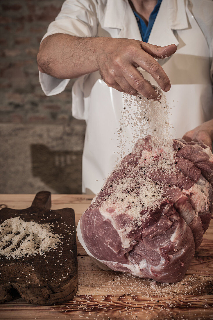 Butcher spicing meat in shop