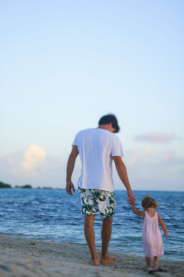 Father and toddler daughter on beach