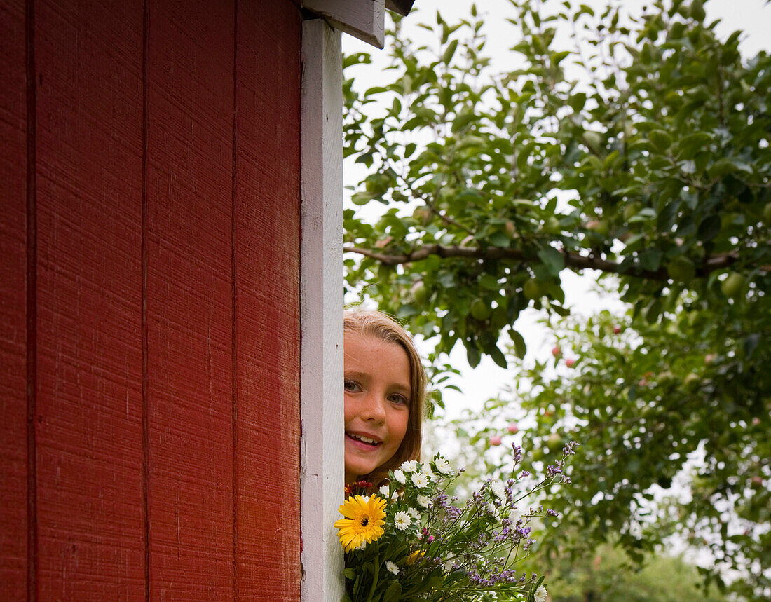 Girl with Flowers Peeking around Shed