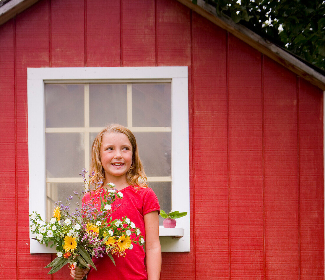 Girl with Flowers Standing in front of Shed