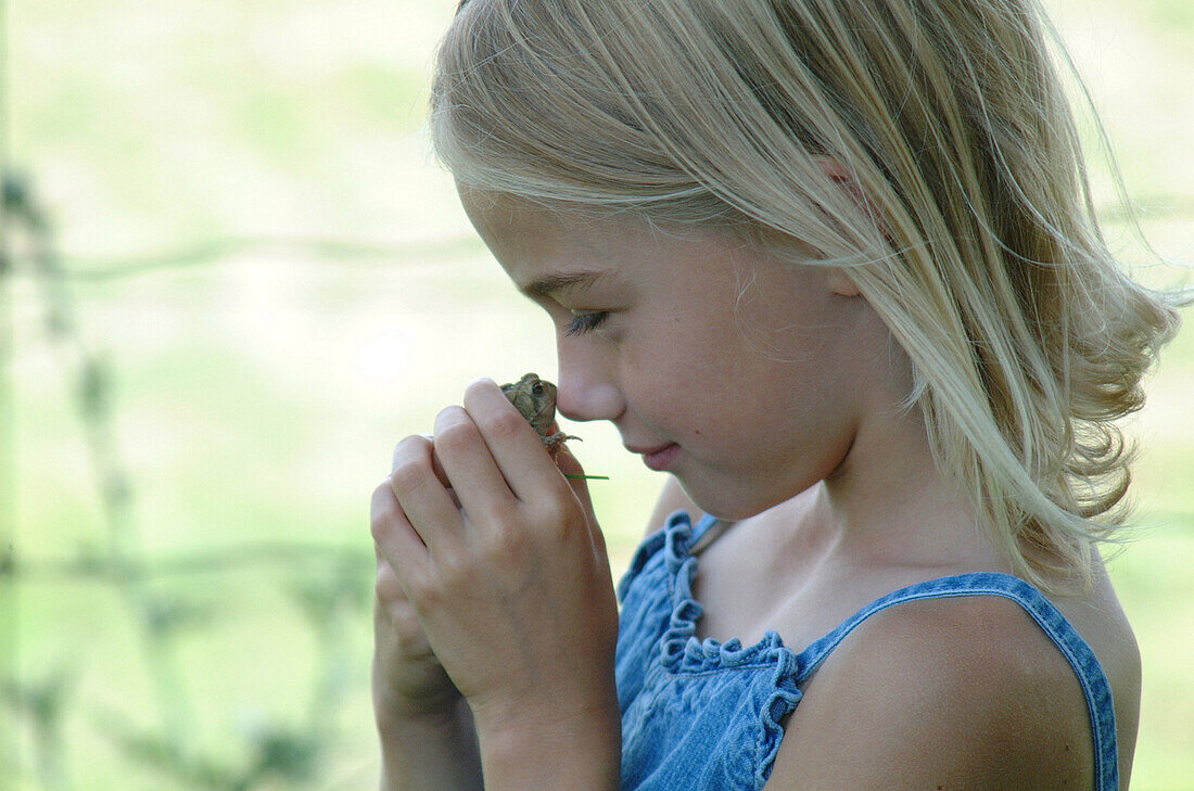 Young Girl Holding Frog to her Nose