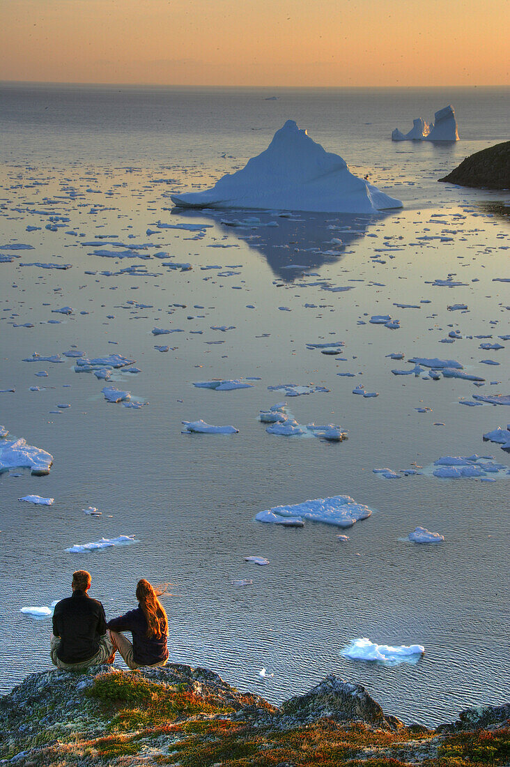 Couple looking out at an Iceberg at Sunset, Twillingate, Newfoundland