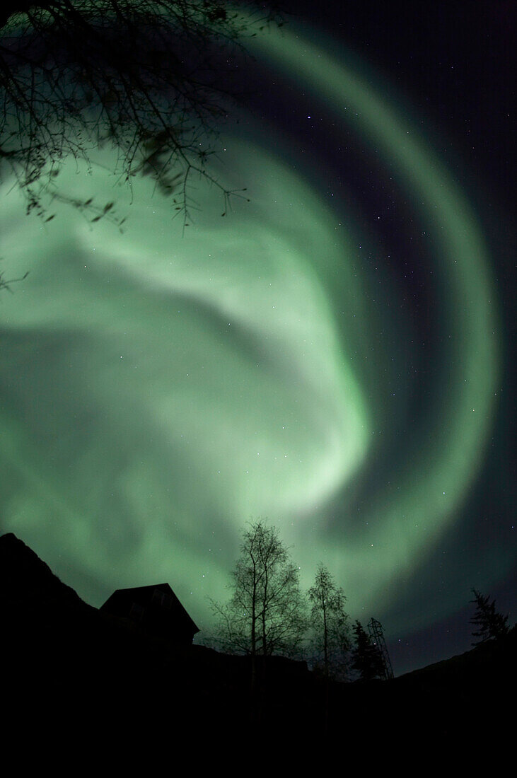 Swirling aurora borealis fills the night sky on the outskirts of the capital city of Yellowknife, Northwest Territories, Canada.