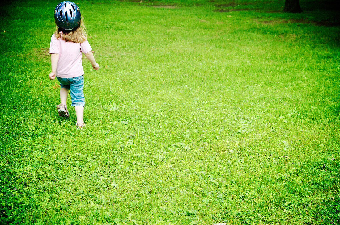 Blond girl with bike helmet running in park, Otterburn Park, Quebec