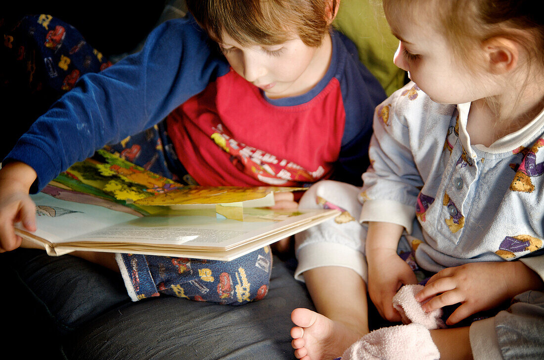 Brother and sister in pajamas reading a book, Otterburn Park, Quebec